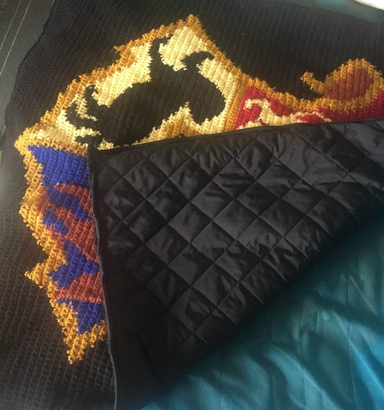 back view of crochet blanket depicting the Hogwarts crest from Harry Potter, showing the quilted backing