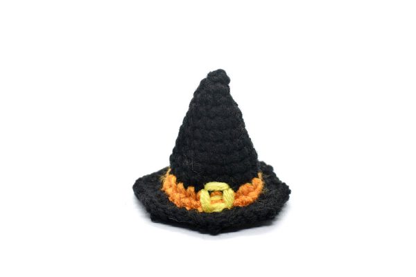 a small crocheted black witch hat with an orange band and a yellow buckle