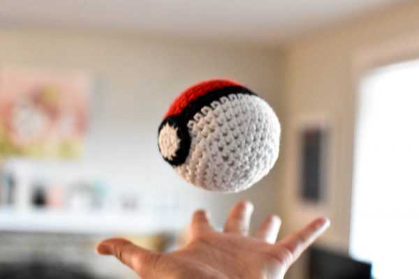 pokeball amigurumi toy being thrown in the air in a living room