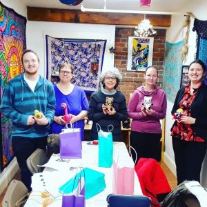 a group of people at a workshop holding crochet dolls