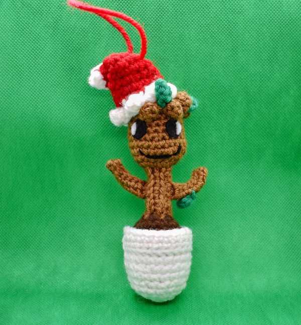 crochet baby groot christmas ornament doll against a green background - front view of doll