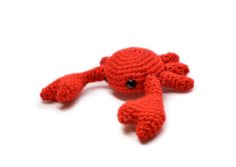 a small crochet crab against a white background