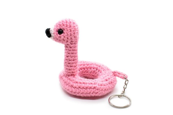 side view of a small crochet flamingo floatie toy keychain against a white background