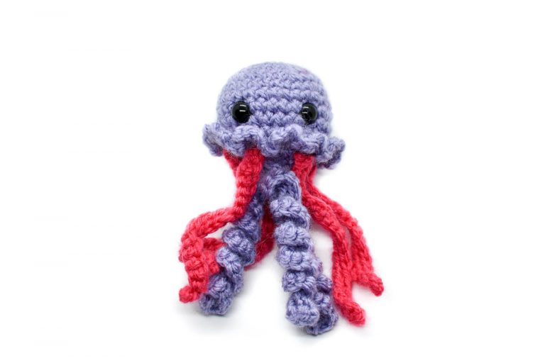 a small crochet purple and pink jellyfish toy against a white background