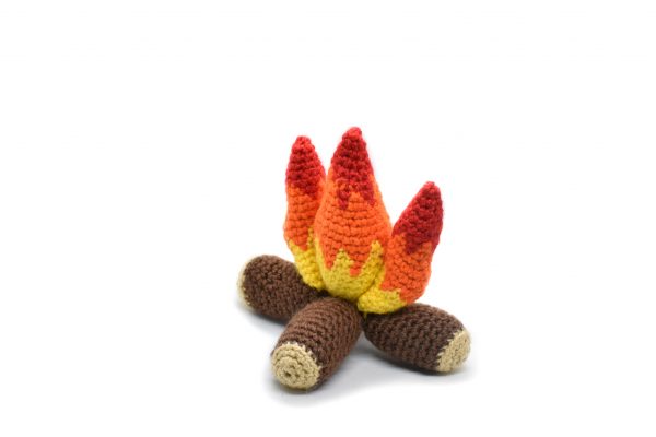 side view of a small plush crochet campfire against a white background