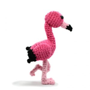 a crochet pink flamingo standing on one leg