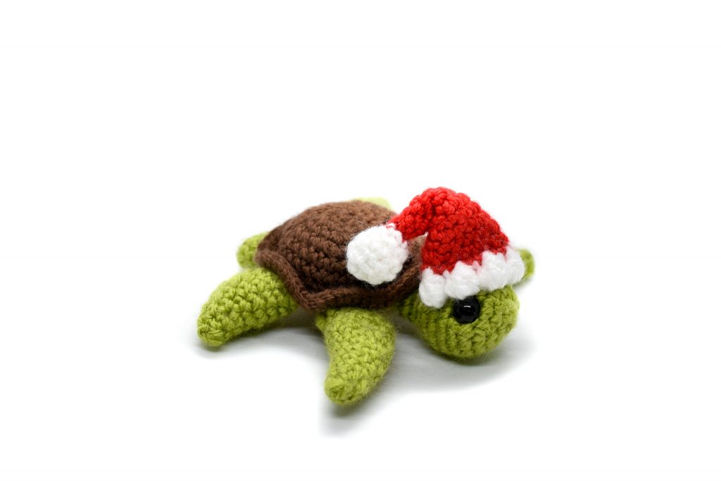 a small crochet turtle wearing a Santa hat