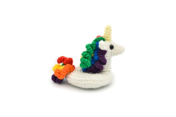 a small crochet unicorn floatie with rainbow coloured hair and tail