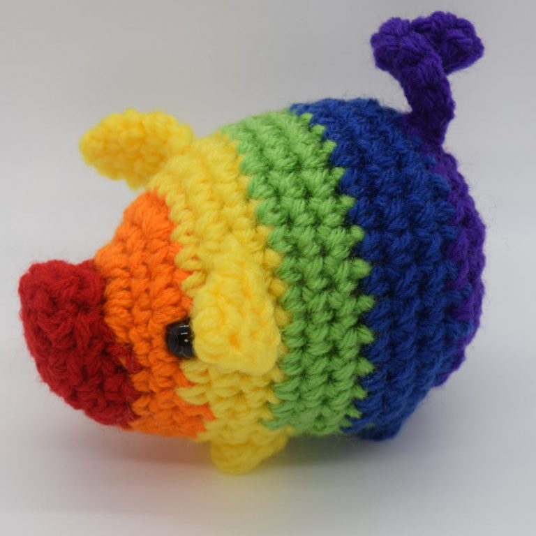 A small and simple crochet pig made in striped rainbow colours