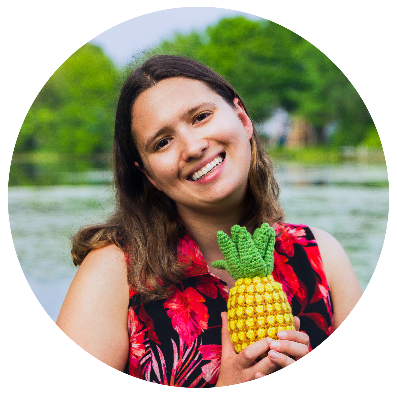 a picture of a young woman standing in front of a lake and holding a crochet pineapple
