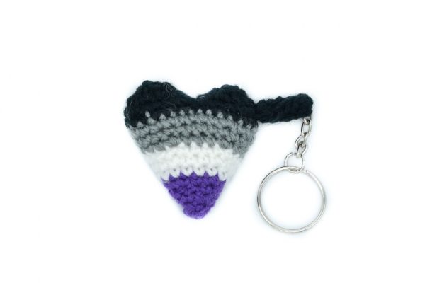 a small crochet heart keychain in the asexual flag colours against a white background. From top to bottom, the colours are: black, grey, white, purple