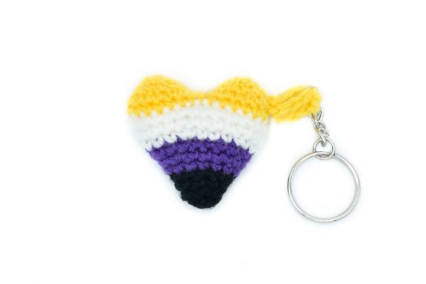 a small crochet heart keychain in the non-binary flag colours against a white background. From top to bottom, the flag colours are: yellow, white, purple, black