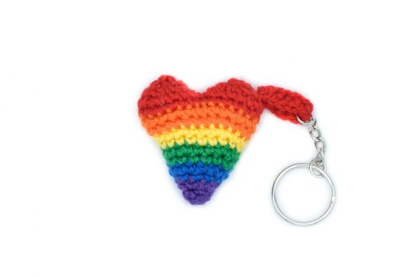 a small crochet heart keychain in the rainbow pride flag colours against a white background.