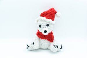 crochet polar bear wearing a red scarf and a Santa hat