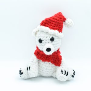 crochet polar bear wearing a red scarf and a Santa hat