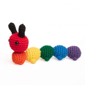 a crochet stuffed caterpillar made in rainbow colours, with the head and each body segment a different colour of the rainbow