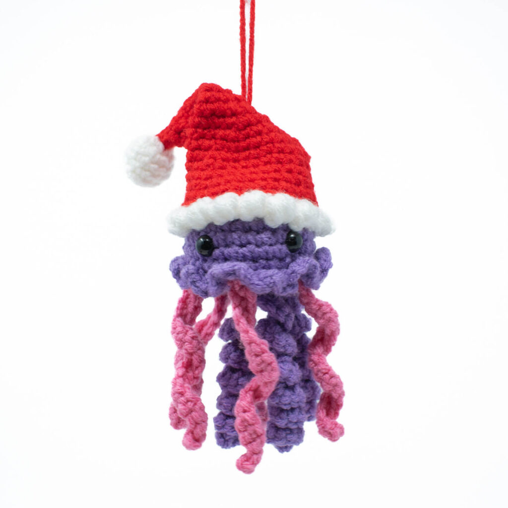 a purple and pink crochet stuffed jellyfish with a Santa hat